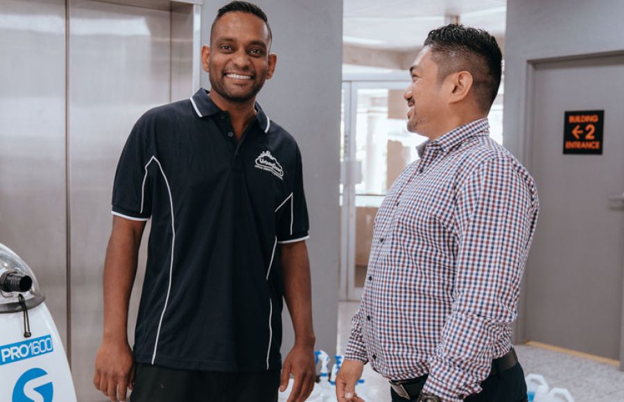 Commercial cleaning contractor shaking hands with a client in an office building foyer.